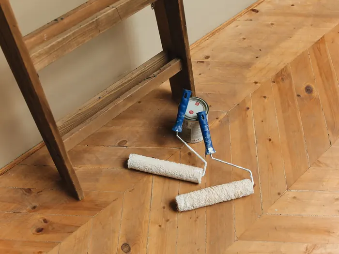 Rouleau de peinture et escabeau sur un parquet en chevrons