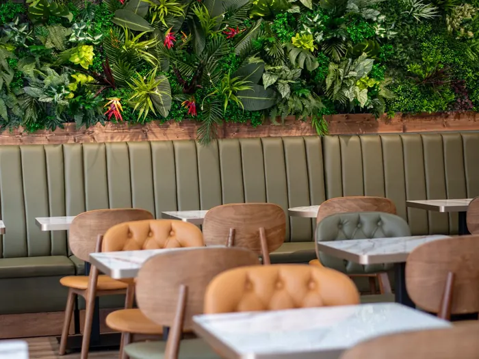 Banquette et chaises capitonnées devant un mur végétal