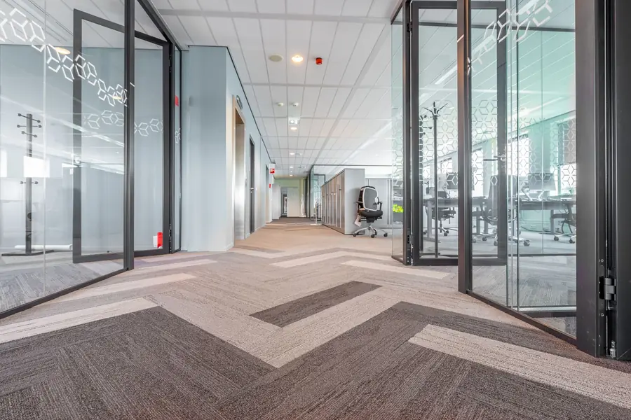 Couloir de bureaux avec moquette et cloisons vitrées